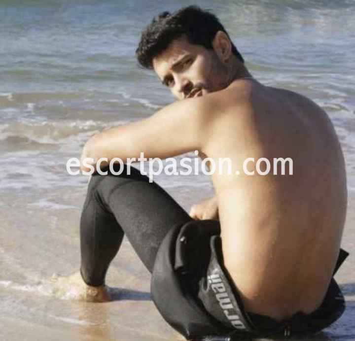 escort gay sentado en la orilla del mar